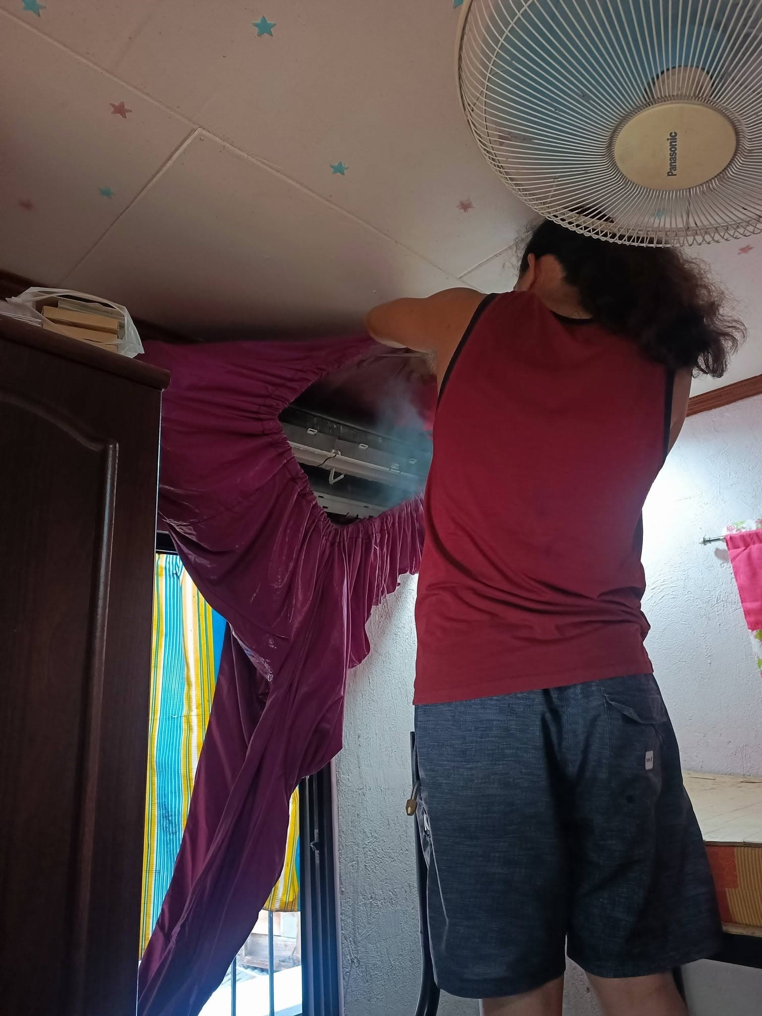 CALA technician deep-cleaning a wall-mounted indoor air conditioner with a protective wash cover.